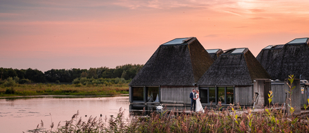 A couple standing on the boardwalk in front of Brockholes Visitor Village at sunset