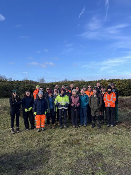 Image of group of volunteers from APEM Limited stood on Freshfield Dune Heath with blue sky