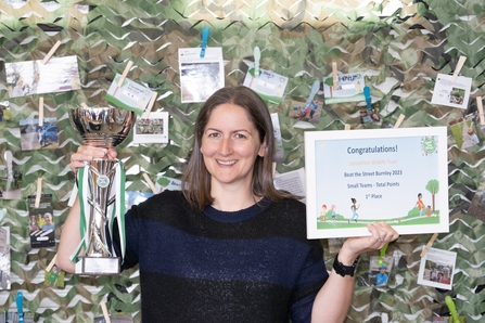 A woman holding a trophy and certificate