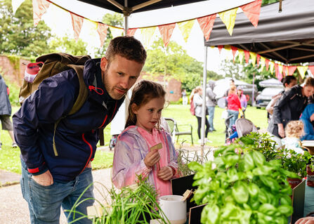 A man and a girl looking at some plants under a gazebo