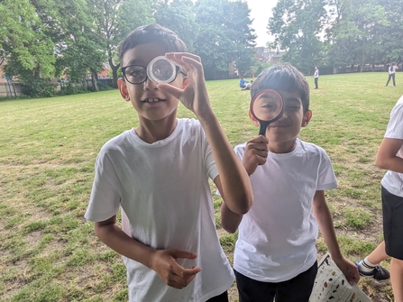 Two children looking through magnifying glasses