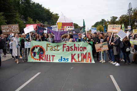 Climate protesters with a sign saying 'fast fashion is killing the climate'