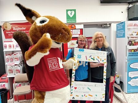  Tweeddale Red Squirrel Network Volunteers stand with their squirrel mascot at a local stall