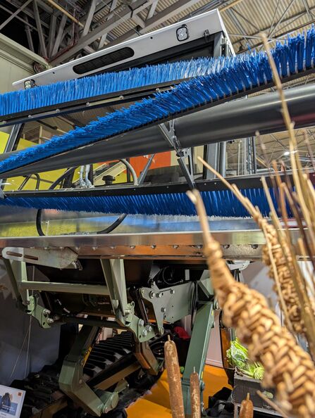 A tractor with a harvest head covered in blue brushes