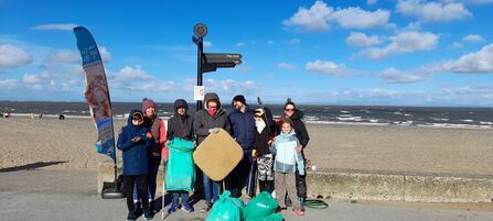 A group of people standing by the beach in Fleetwood with rubbish collected off the beach