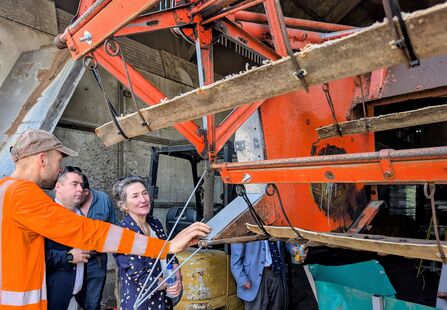 Three people look at a bulrush harvesting machine