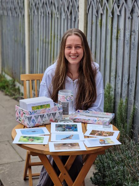Delphine sitting down at a table with her photographs fundraising 