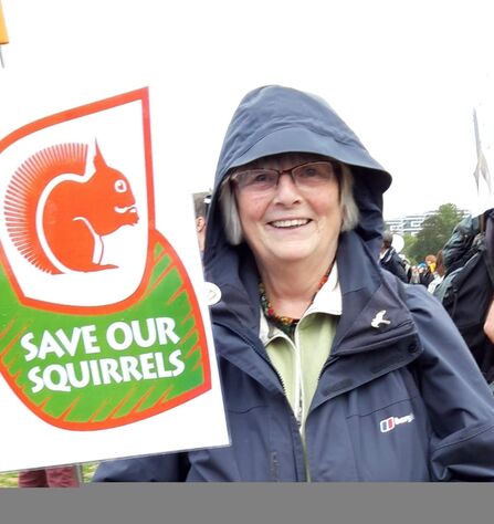 Volunteer Maureen with a 'Save our squirrels' sign at Chris Packham's People's Walk for Wildlife
