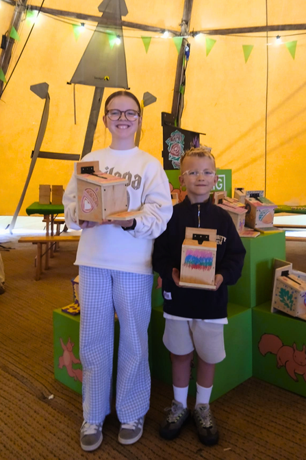 Young people posing with red squirrel feeders