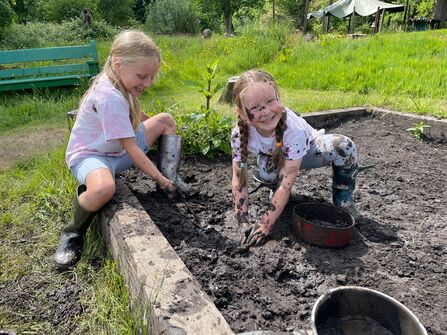 Two children having fun playing in the mud pit at The Hive