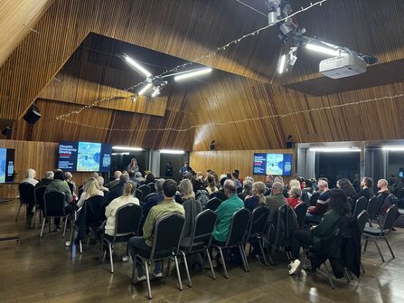 Rows of people sitting down to watch a screening of the People's Emergency Briefing at Brockholes
