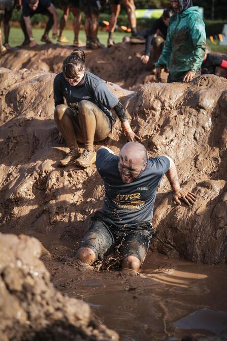 Two people sliding down a muddy hill