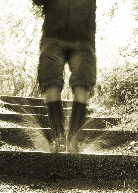 A man jumping in a puddle wearing wellies