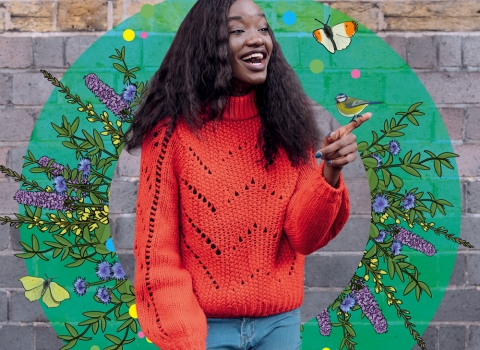 A girl in an orange jumper surrounded by beautiful wildlife illustrations