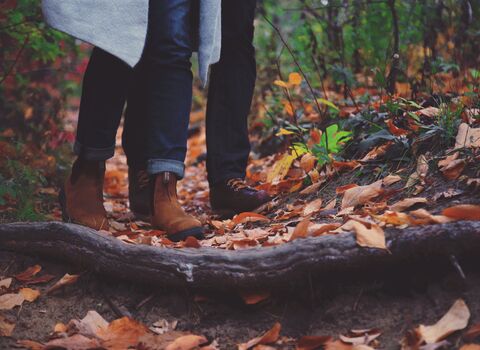 A couple walking through autumn leaves in a woodland