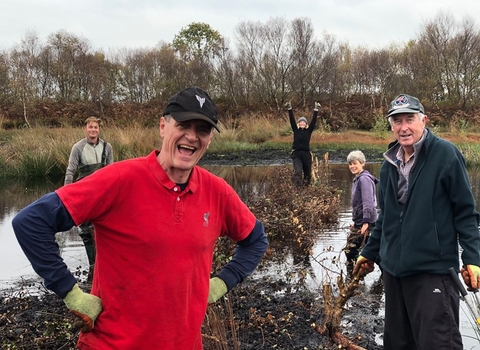 Group of 5 volunteers building a dead hedge in an area of open water on Little Woolden Moss