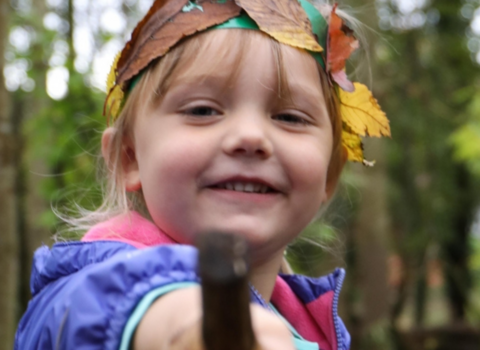 Girls with a leaf crown and pointing with a stick