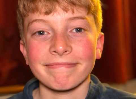 Monty smiling at an indoor event with a curtain in the background. 