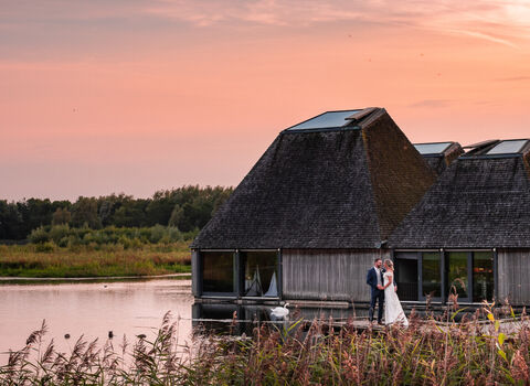 A couple standing on the boardwalk in front of Brockholes Visitor Village at sunset