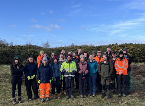 Image of group of volunteers from APEM Limited stood on Freshfield Dune Heath with blue sky
