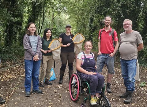 A group of volunteers, including a wheelchair user, some with butterfly nets