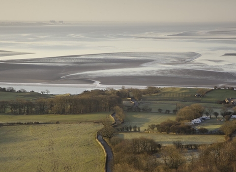 A sweeping view over open fields to Morecambe Bay from Arnside Knott